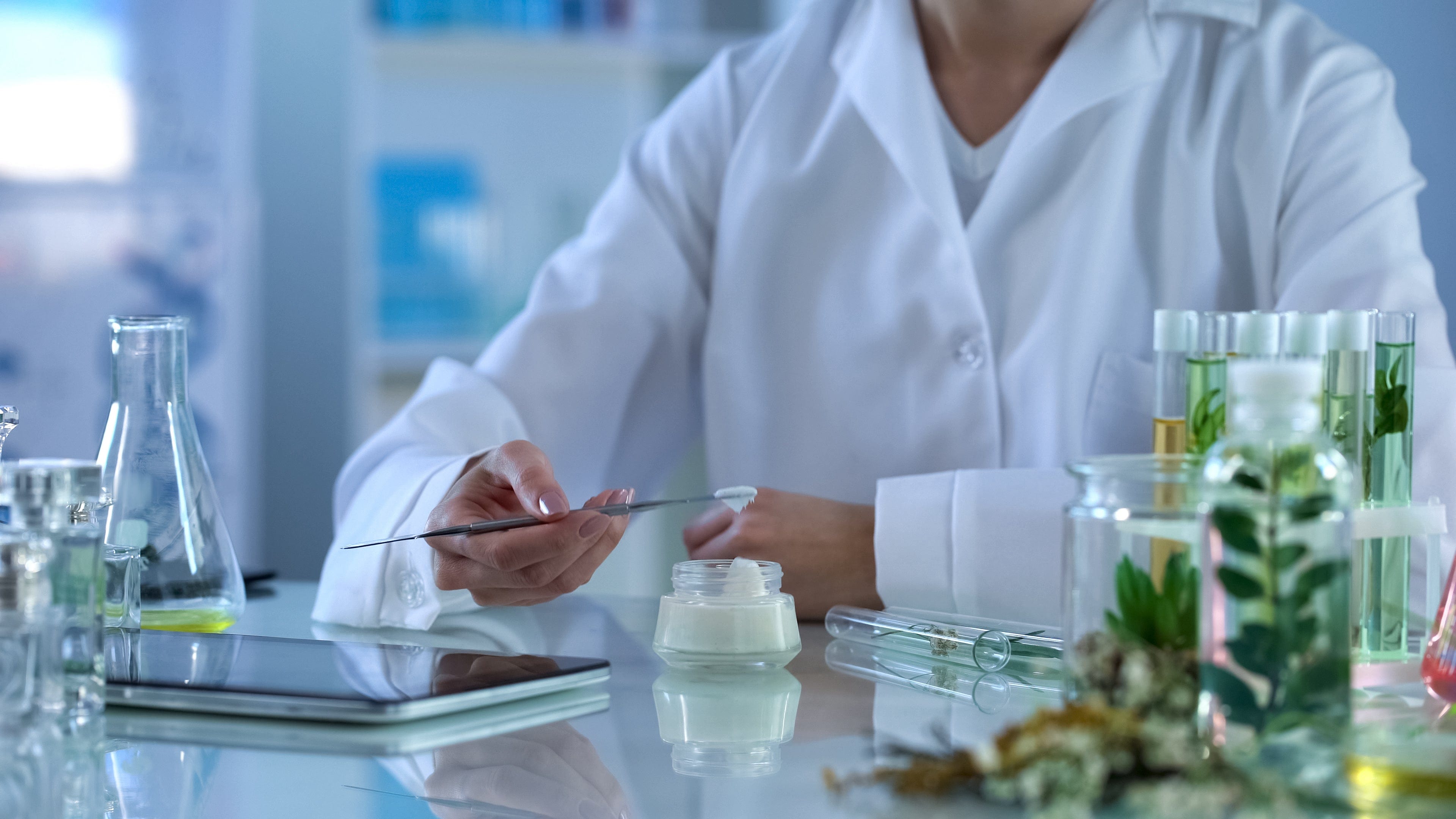 Lab technician in a white coat preparing a skincare formulation, surrounded by test tubes and natural ingredients, symbolizing Pravada’s commitment to quality in private label skincare development.